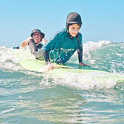 Le moniteur de surf choisit la bonne vague et donne un coup de pouce à la planche