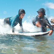 Avec une petite impulsion, le coach propulse ton enfant dans la vague – première sensation de surf garantie !