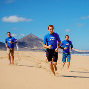 Tu fais un petit jogging le long de la plage infinie – échauffement parfait pour commencer ton cours de surf à Fuerteventura.
