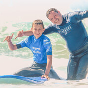 Tu surfs aux côtés de ton enfant – une aventure partagée et un souvenir inoubliable.