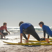 Moniteur de surf montrant les mouvements de take-off à sec pendant un cours pour débutants.