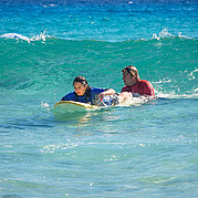 Un moniteur de surf pousse son élève dans la vague
