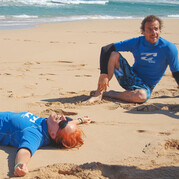Élève satisfait se repose sur la plage après une session intense de surf.